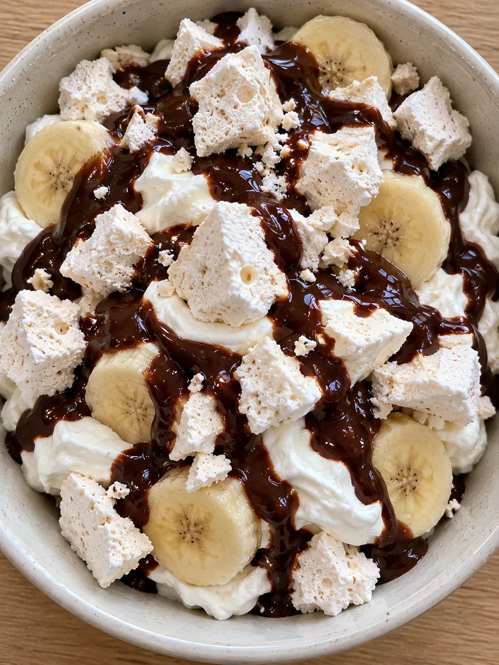 Marängsviss med banan, spröda marängbitar och chokladsås ringlad över grädden
